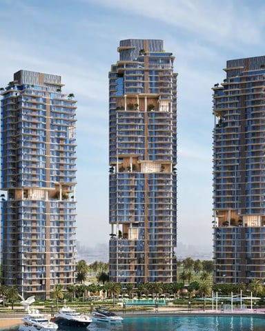 Three modern waterfront residential towers with blue glass and gold accents, palm trees, and boats in foreground