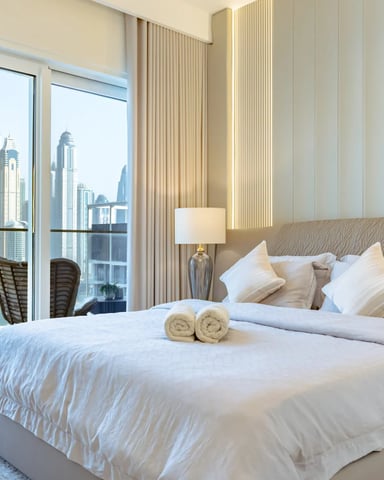 Luxury high-rise bedroom with floor-to-ceiling windows overlooking downtown skyline and waterfront